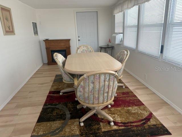 A dining area features a light wood table, four patterned chairs, and a fireplace — 294 COLONIAL BOULEVARD UNIT 48, PALM HARBOR, FL