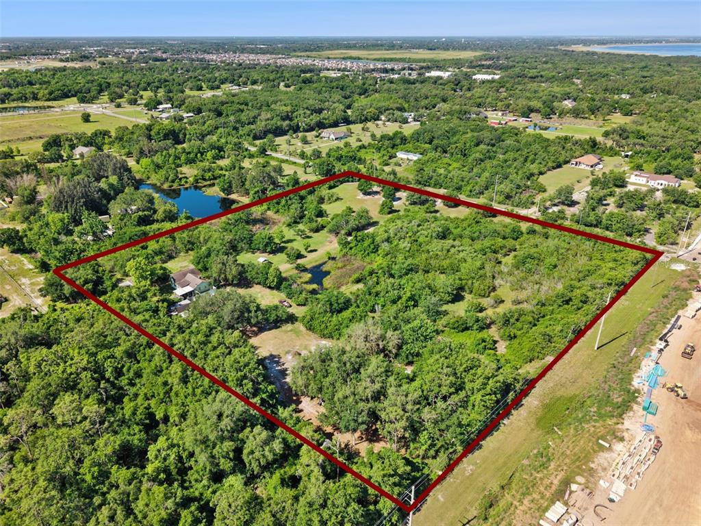 An aerial view shows a large, wooded plot of land outlined in red with a house — 1235 HACKNEY ROAD, ST CLOUD, FL