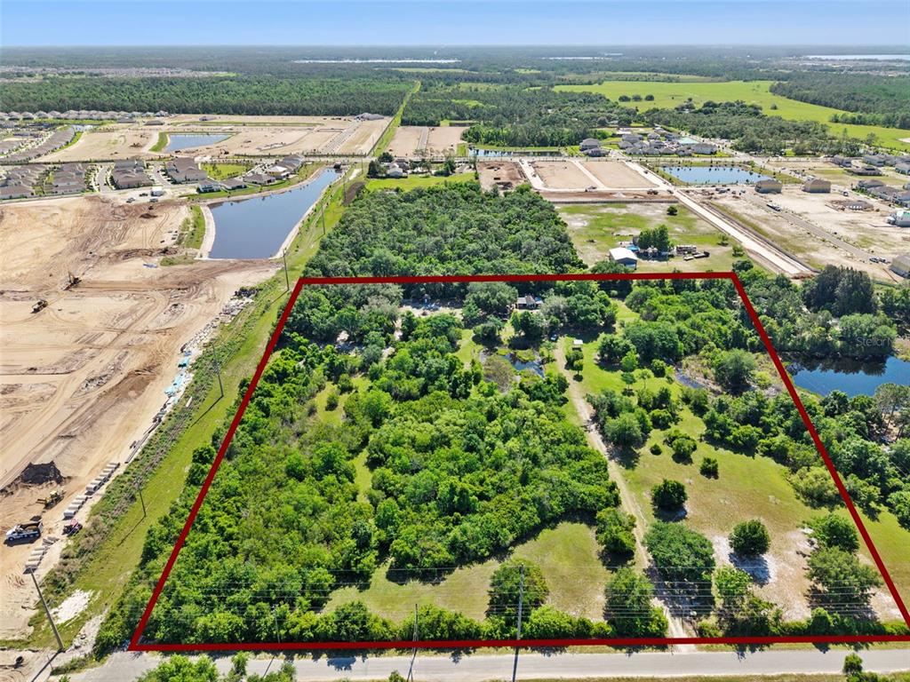 An aerial view shows a large, rectangular plot of land surrounded by trees and development — 1235 HACKNEY ROAD, ST CLOUD, FL