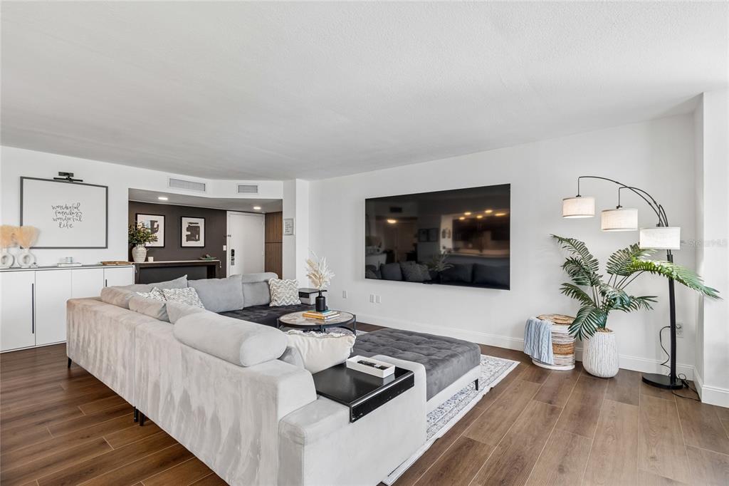 A living room with a large gray sectional sofa, open kitchen, and floor-to-ceiling windows — 644 ISLAND WAY UNIT 405, CLEARWATER, FL
