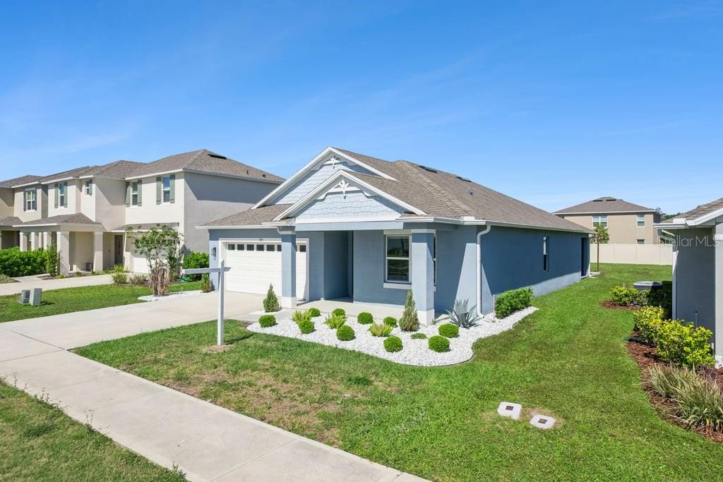 A single-story blue house with a two-car garage and a landscaped front yard — 5235 MAHOGANY DRIVE, MOUNT DORA, FL