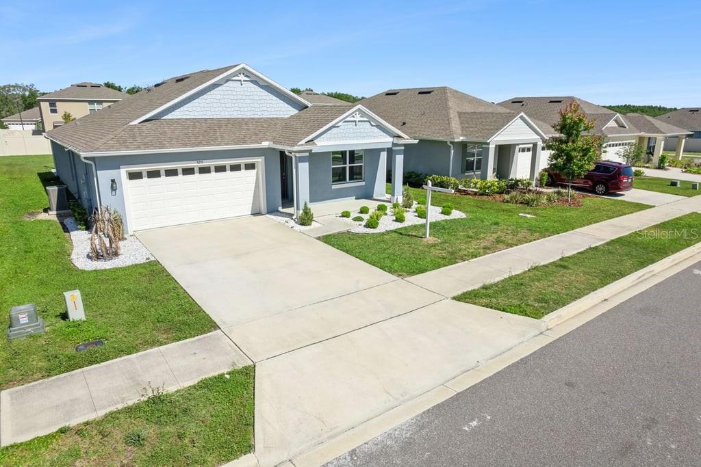 A single-story suburban house with a two-car garage, light blue siding, and a concrete driveway — 5235 MAHOGANY DRIVE, MOUNT DORA, FL