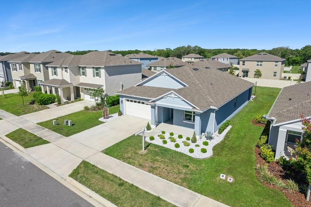 An aerial view shows a light blue single-story house with a white garage and landscaping — 5235 MAHOGANY DRIVE, MOUNT DORA, FL
