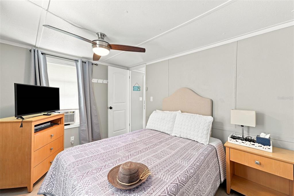 A bedroom features a bed with a patterned quilt, a wooden dresser, and a ceiling fan — 6819 HERON LANE, HUDSON, FL