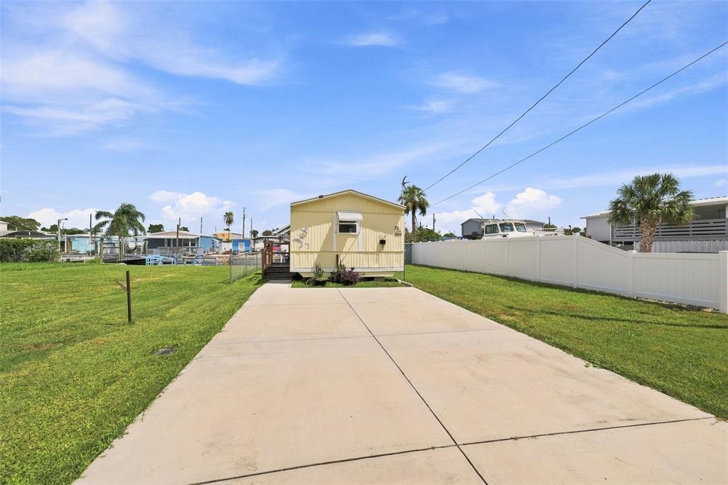 A yellow mobile home sits at the end of a concrete driveway on a grassy lot — 6819 HERON LANE, HUDSON, FL