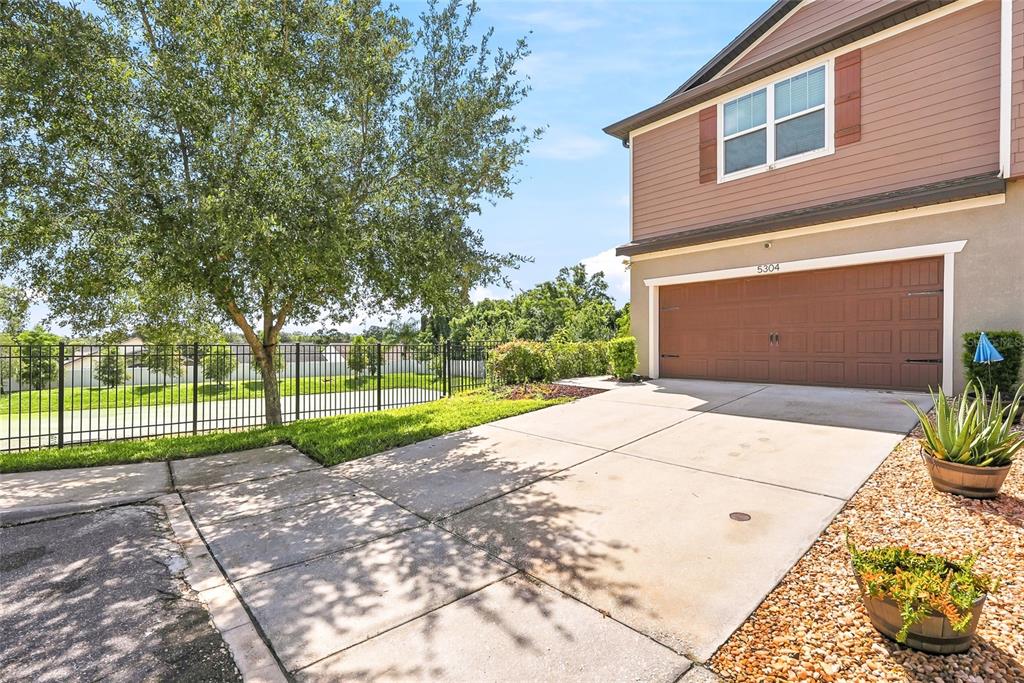 A two-story house exterior features a brown garage, a concrete driveway, and a fenced yard — 5304 SYLVESTER LOOP, TAMPA, FL