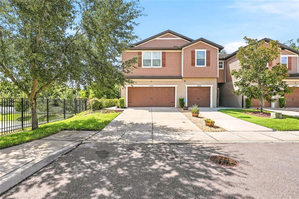 A two-story townhouse with two garage doors and a concrete driveway under a blue sky — 5304 SYLVESTER LOOP, TAMPA, FL