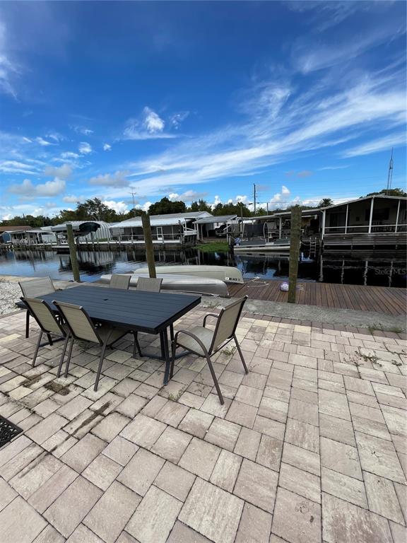 A patio with a dining set overlooks a canal with boat docks and mobile homes — 21728 73 LANE, VERO BEACH, FL
