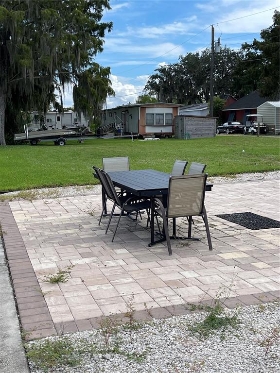 A patio with a dining set sits on a lawn near mobile homes and trailers — 21728 73 LANE, VERO BEACH, FL