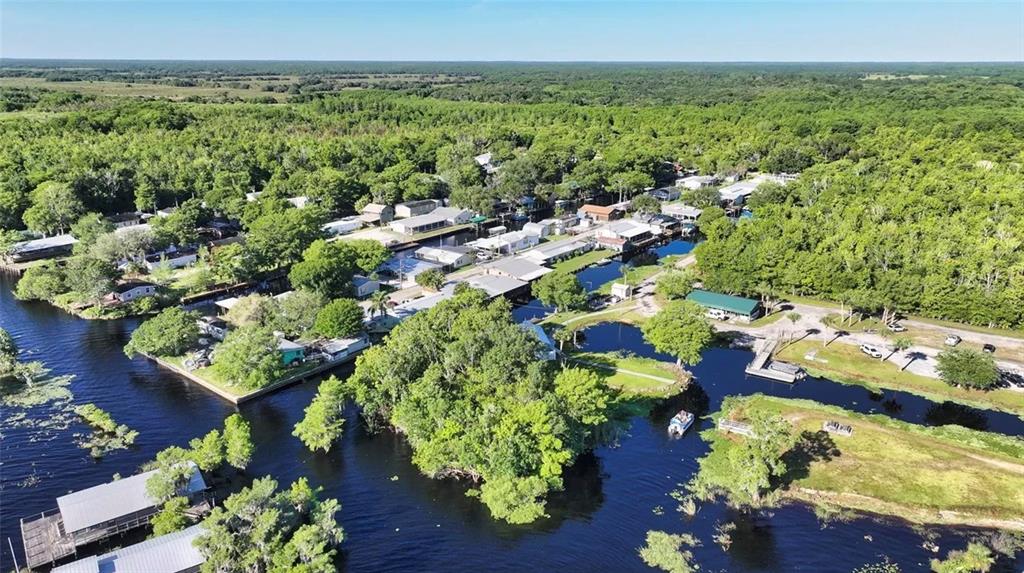 An aerial view shows a residential community with houses situated along narrow canals and trees — 21728 73 LANE, VERO BEACH, FL