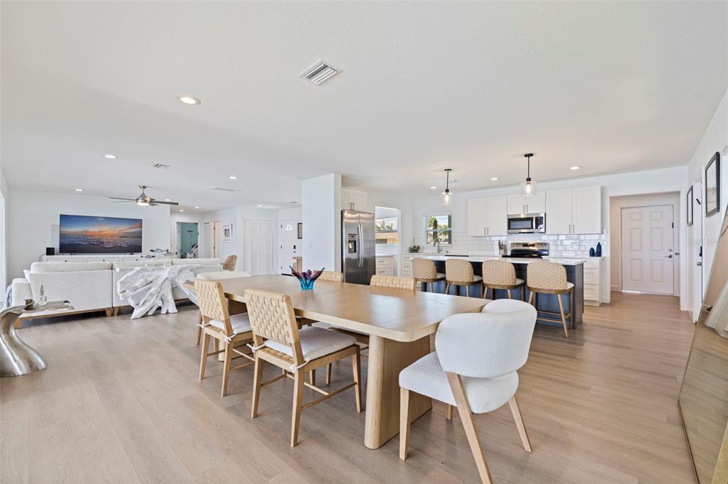 An open-concept living and dining area features light wood flooring, white cabinetry, and modern furniture — 501 22ND AVENUE SE, ST PETERSBURG, FL