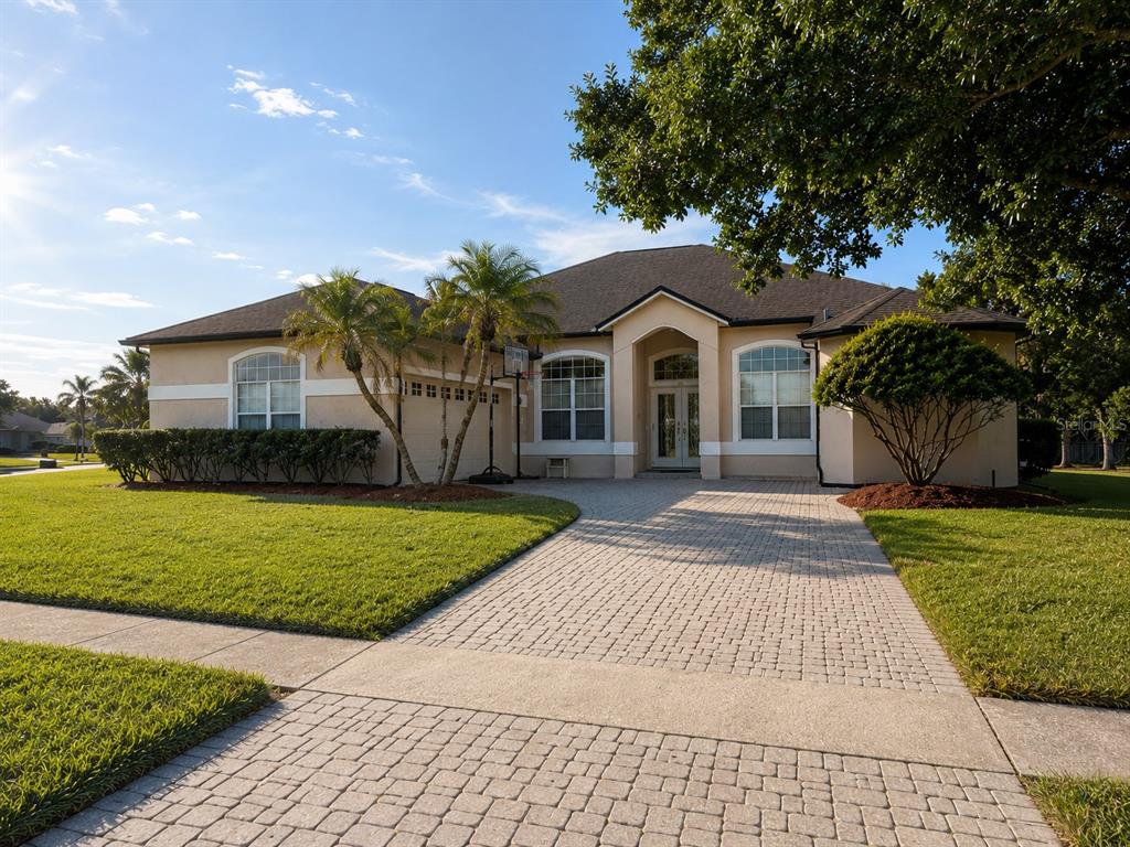 A single-story house with a paved driveway, palm trees, and a green lawn — 4419 SADDLEWORTH CIRCLE, ORLANDO, FL