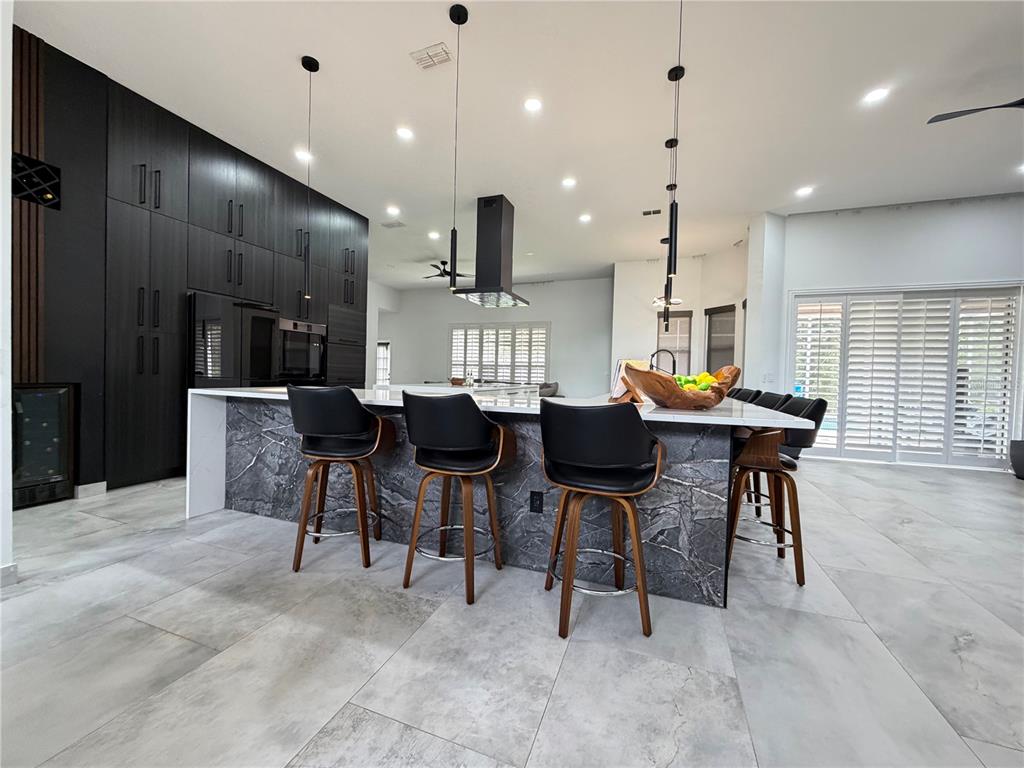 A modern kitchen features a large marble-faced island, black cabinetry, and bar stools — 4419 SADDLEWORTH CIRCLE, ORLANDO, FL