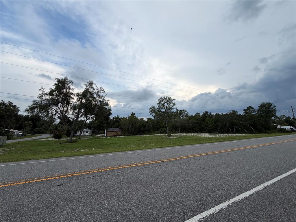A vacant, grassy lot sits alongside a paved road under a cloudy sky — COUNTY ROAD 42, DELAND, FL
