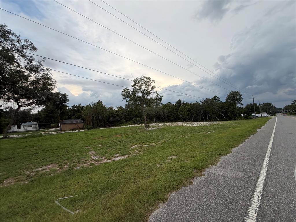 A grassy, vacant lot sits beside a paved road under a cloudy sky — COUNTY ROAD 42, DELAND, FL