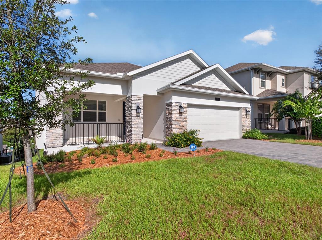 A single-story house with a stone-accented facade, a two-car garage, and a front porch — 1283 DORA PARC LANE, MOUNT DORA, FL