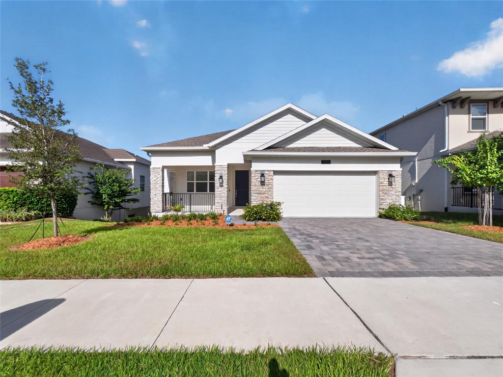 A single-story suburban house features a stone facade, a two-car garage, and a front porch — 1283 DORA PARC LANE, MOUNT DORA, FL
