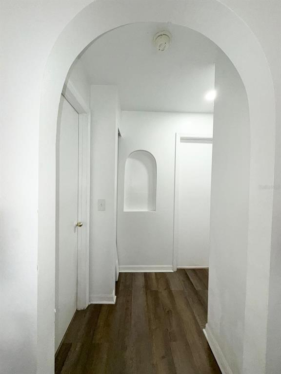 A hallway with white walls, an arched entryway, a wall niche, and wood-look flooring — 409 TALQUIN COURT, ORLANDO, FL