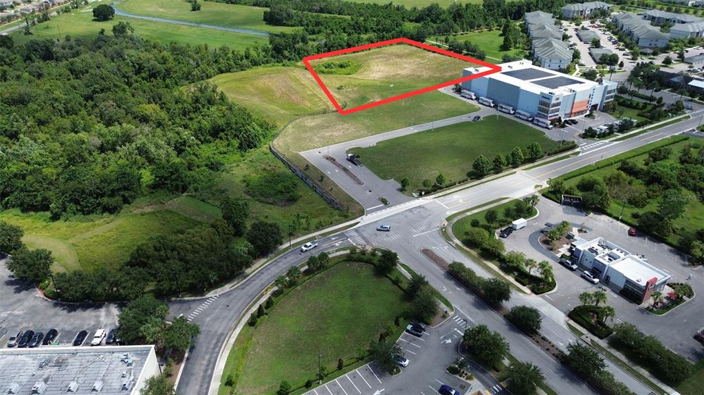 An aerial view shows a vacant rectangular lot outlined in red next to a commercial building — FOUNTAINS WEST BOULEVARD, OCOEE, FL