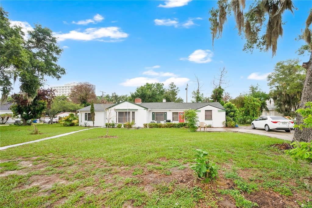 A single-story white house with a green roof sits on a large grassy lot — 715 AVENUE B SW, WINTER HAVEN, FL
