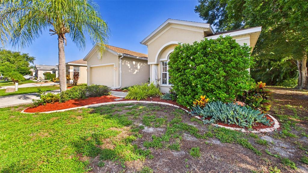 A single-story house with a beige stucco exterior, a garage, and a landscaped front yard — 4021 3RD AVENUE E, BRADENTON, FL