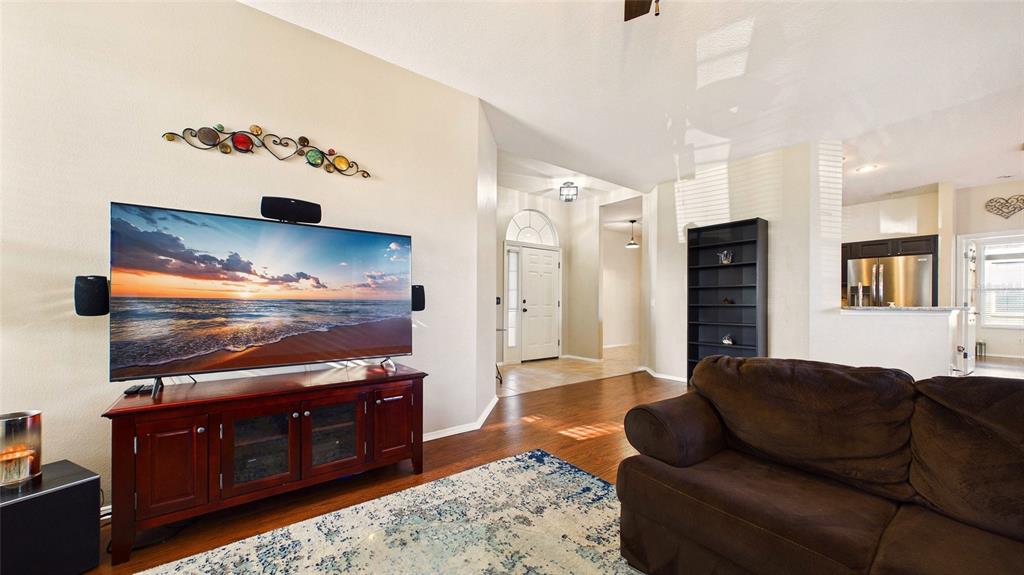 A living room features a large television on a wooden stand, a brown sofa, and hardwood floors — 4021 3RD AVENUE E, BRADENTON, FL