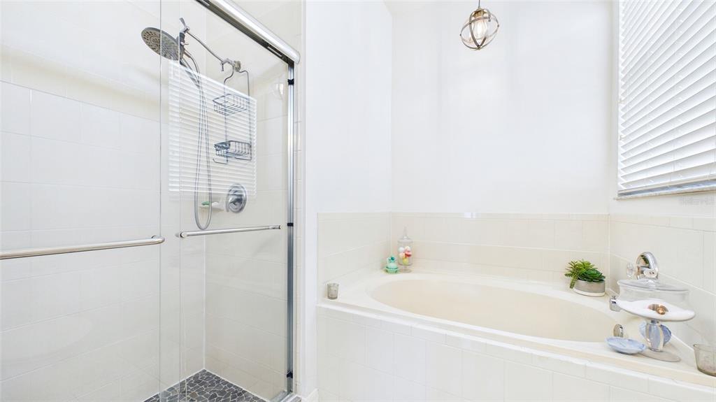A bathroom features a glass-enclosed shower, a built-in soaking tub, and white tiled walls — 4021 3RD AVENUE E, BRADENTON, FL