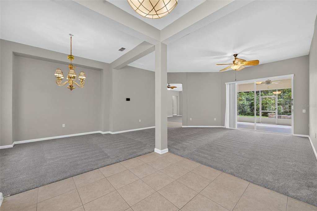 A living and dining area with gray carpet, tile flooring, a chandelier, and sliding glass doors — 2213 WANDERING OAK TERRACE, KISSIMMEE, FL