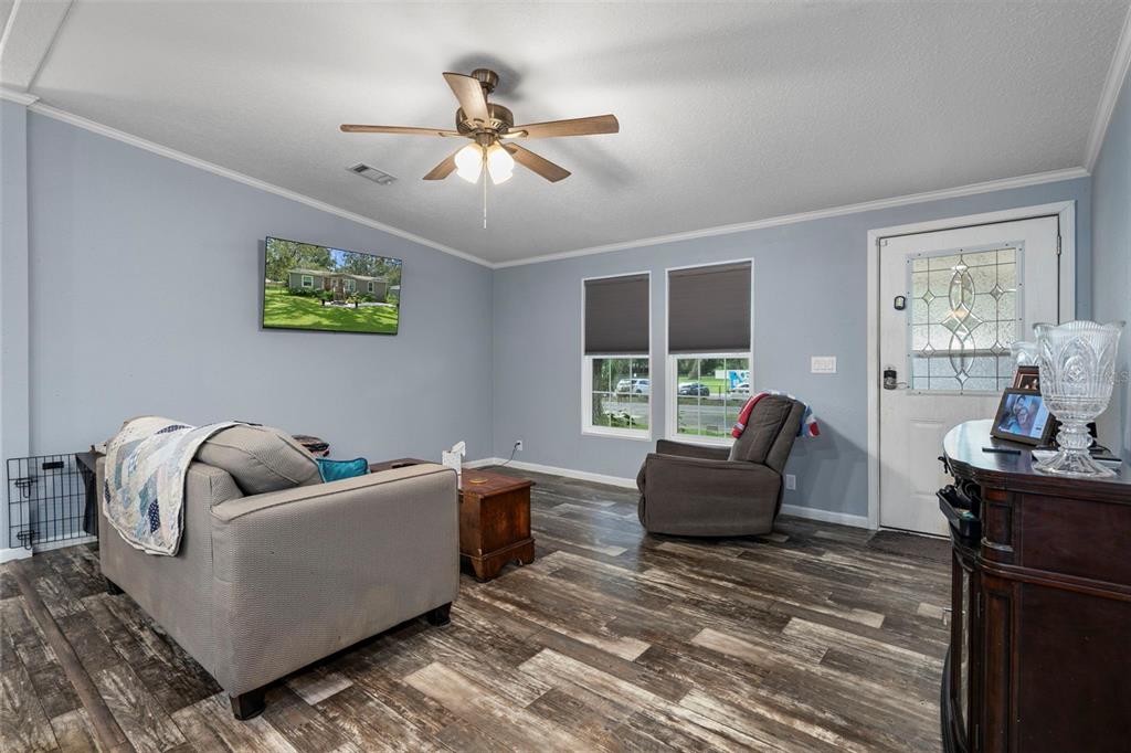 A living room features light blue walls, wood-look flooring, a ceiling fan, and a front door — 9028 WEST STREET, BROOKSVILLE, FL