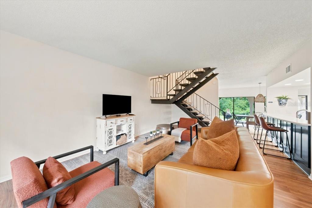 A living room features a staircase, a leather sofa, two armchairs, and a kitchen counter — 5444 SADDLEBROOK WAY UNIT 2, WESLEY CHAPEL, FL