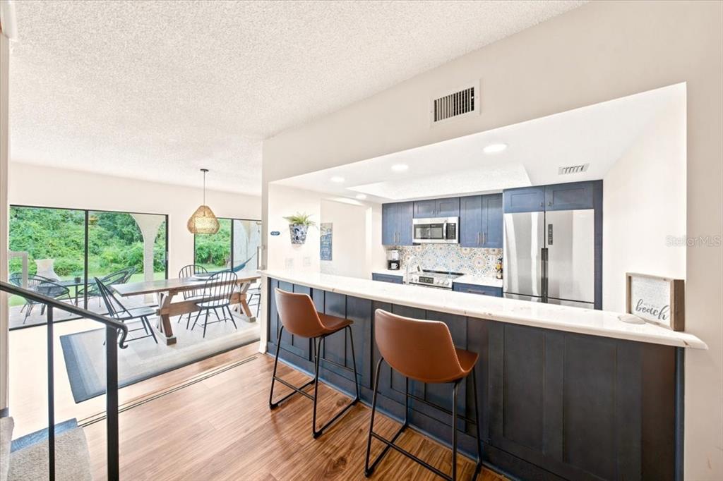 A kitchen with blue cabinets and a breakfast bar overlooks a dining area with patio access — 5444 SADDLEBROOK WAY UNIT 2, WESLEY CHAPEL, FL