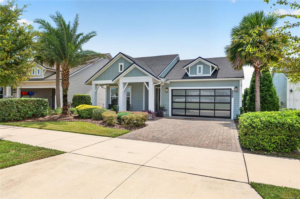 A single-story house with a light blue exterior, a paved driveway, and a modern garage door — 12027 SW 33RD PLACE, GAINESVILLE, FL