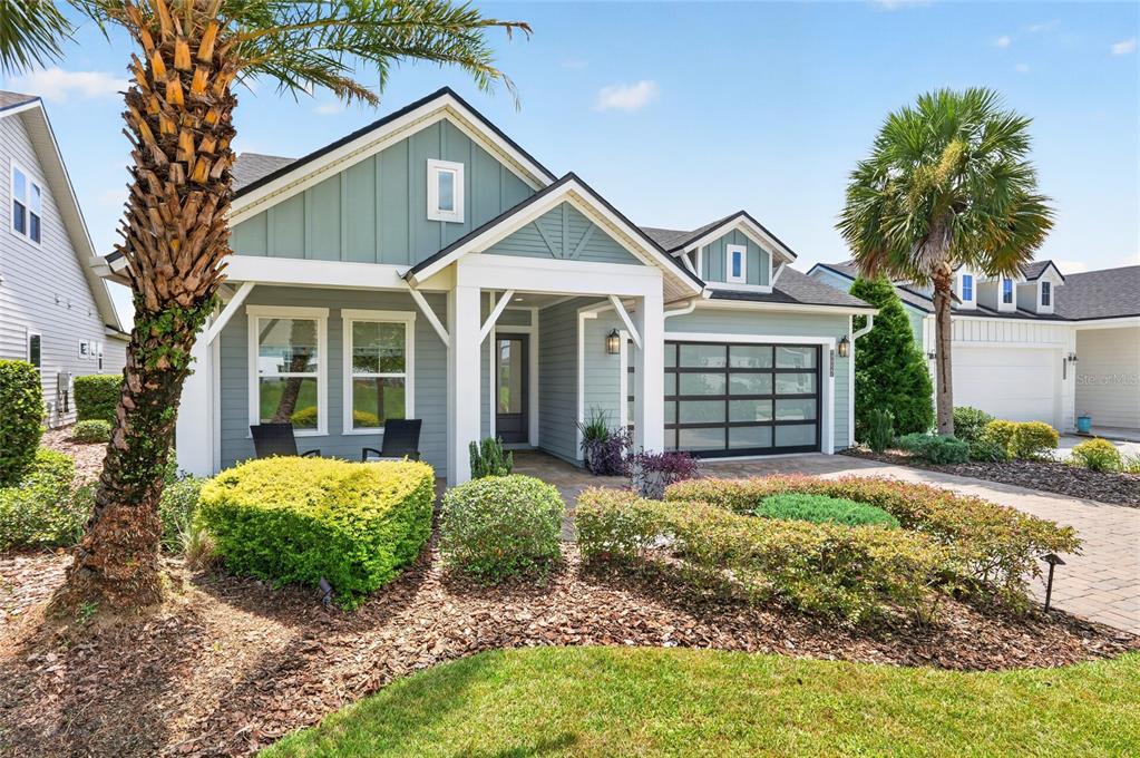 A single-story house with light blue siding, a glass garage door, and a palm tree — 12027 SW 33RD PLACE, GAINESVILLE, FL