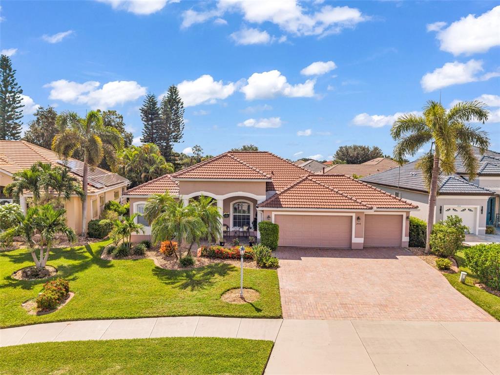 A single-story house with a tiled roof, a three-car garage, and a brick paver driveway — 2450 SILVER PALM ROAD, NORTH PORT, FL