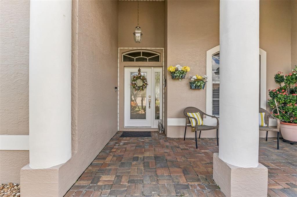 A covered entryway features a paver floor, two white columns, and a glass-paneled front door — 2450 SILVER PALM ROAD, NORTH PORT, FL