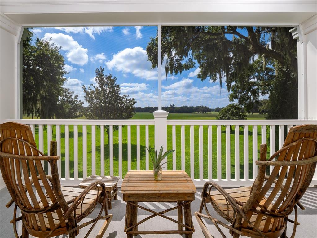 A screened-in porch features two wooden rocking chairs and a small table overlooking a field — 3682 W HIGHWAY 318, CITRA, FL