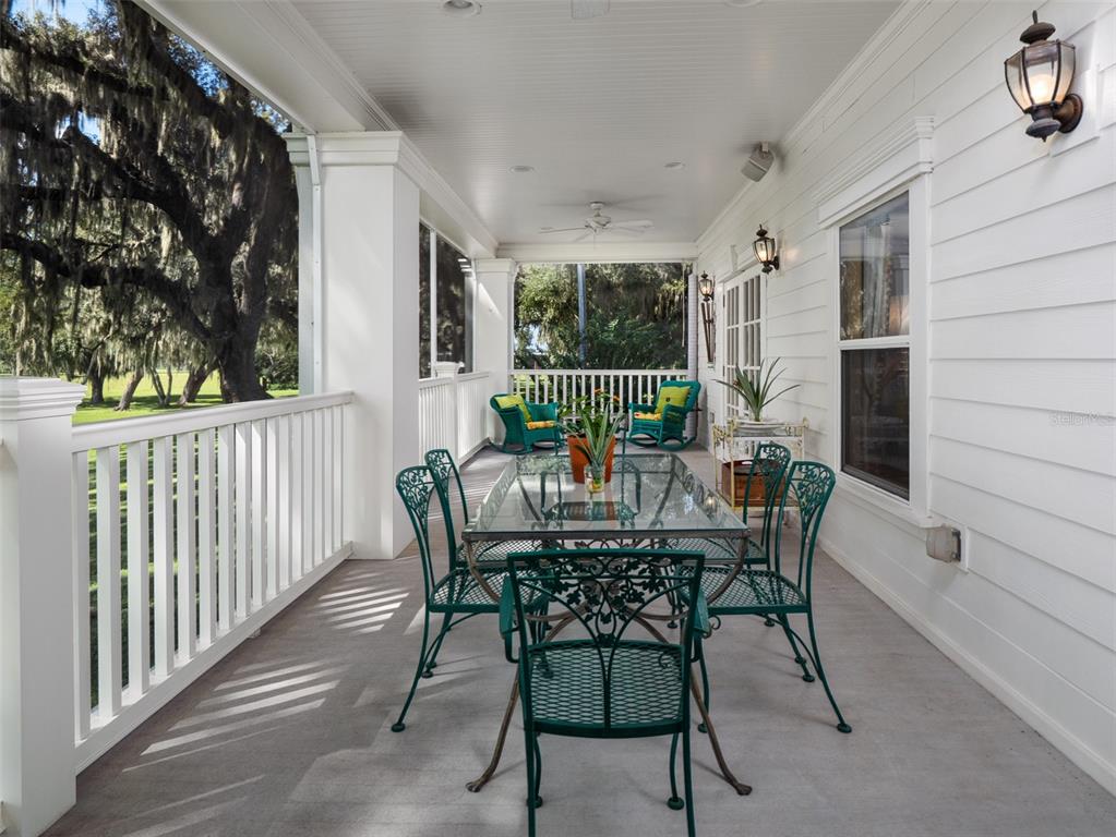 A covered porch features a glass-top dining table with green metal chairs and white railings — 3682 W HIGHWAY 318, CITRA, FL