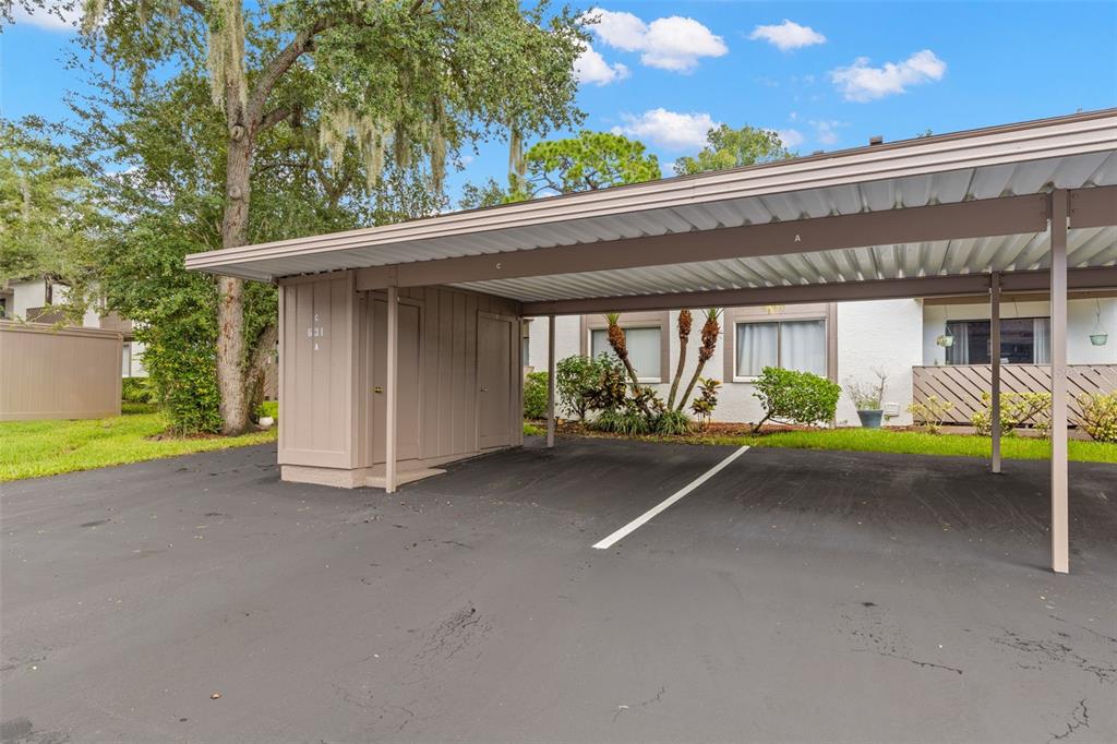 A covered parking carport with storage units stands in front of a residential building — 631 FAIRMONT AVENUE UNIT C, SAFETY HARBOR, FL