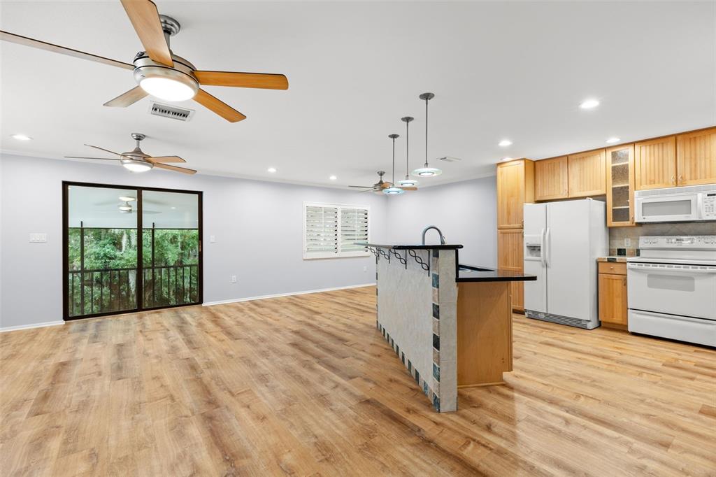 An open-concept kitchen and living area features wood-look flooring, a breakfast bar, and ceiling fans — 631 FAIRMONT AVENUE UNIT C, SAFETY HARBOR, FL