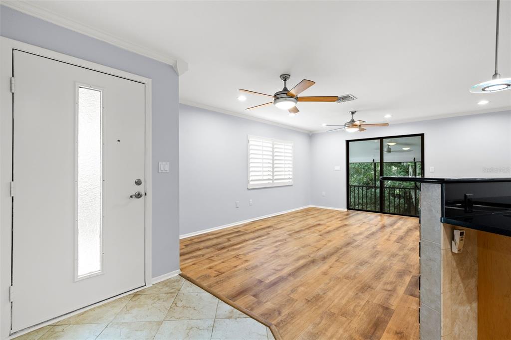 A living room with wood-look flooring, two ceiling fans, and a sliding glass door — 631 FAIRMONT AVENUE UNIT C, SAFETY HARBOR, FL