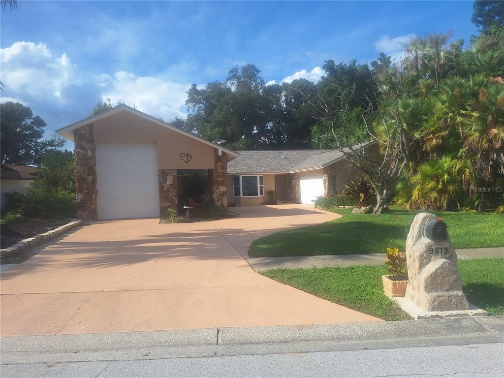 A single-story house with a stone-accented facade, a large driveway, and a prominent mailbox — 9613 LEEWARD AVENUE, LARGO, FL
