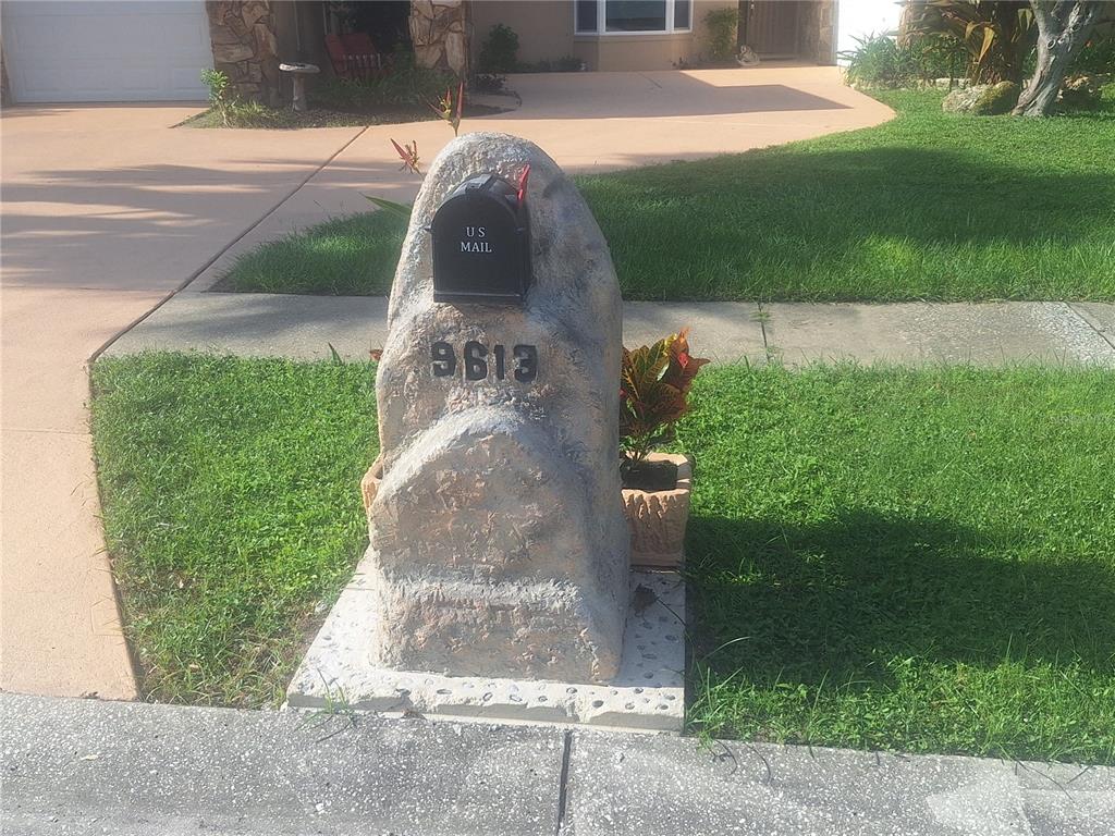 A stone-textured mailbox structure with the house number 9613 sits on a concrete base — 9613 LEEWARD AVENUE, LARGO, FL