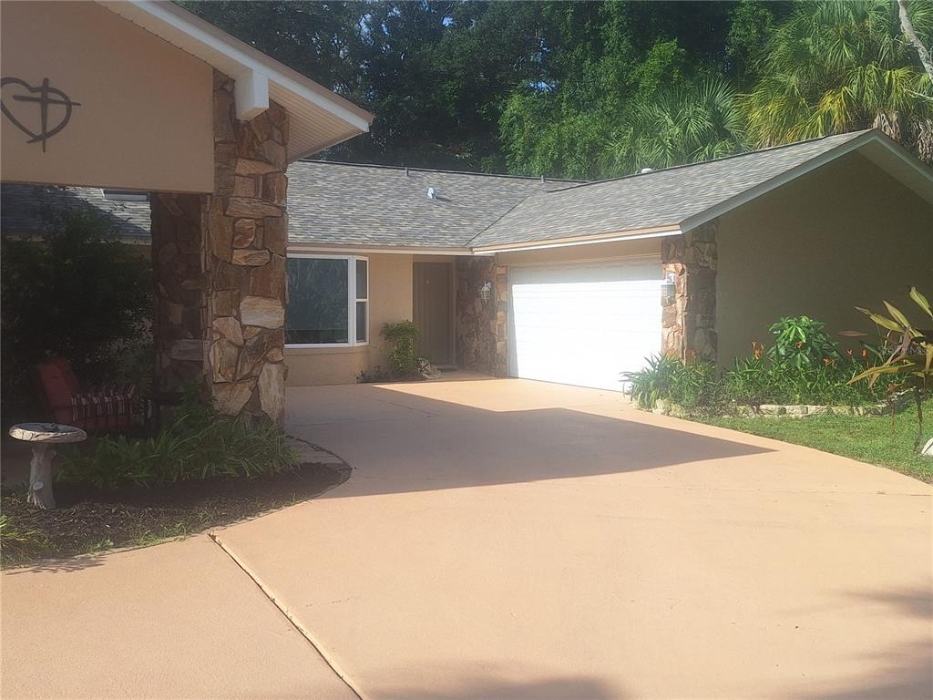A single-story house with a stone-accented facade, a two-car garage, and a paved driveway — 9613 LEEWARD AVENUE, LARGO, FL