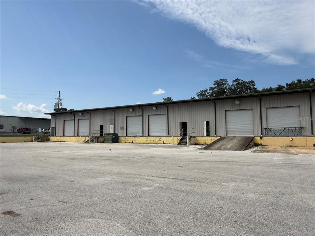An exterior view of a commercial warehouse building with multiple loading dock doors and ramps — 5042 W HIGHWAY 40 UNIT 101, OCALA, FL