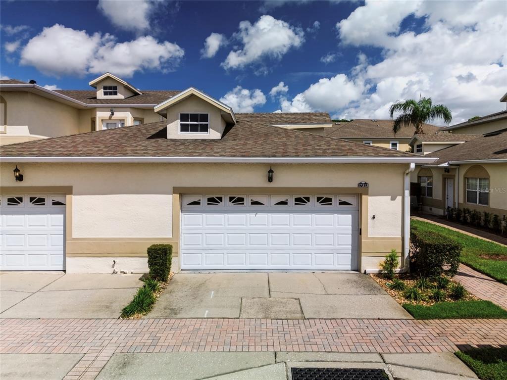 A single-story house with a white stucco exterior, a garage, and a brick walkway — 17313 CHATEAU PINE WAY, CLERMONT, FL