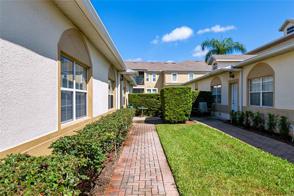 A two-story townhouse exterior features two white garage doors, a brick walkway, and a lamppost — 17313 CHATEAU PINE WAY, CLERMONT, FL