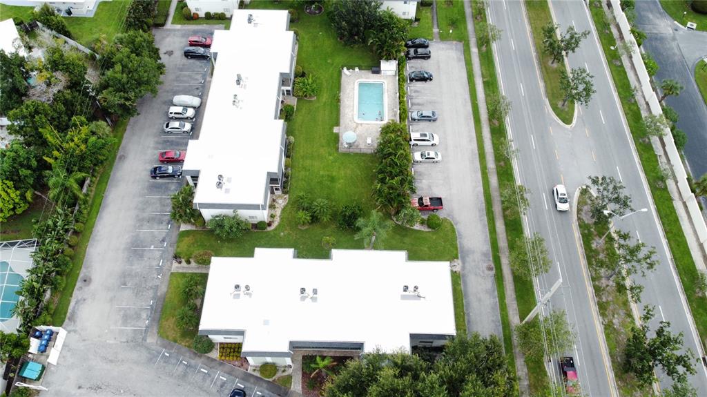 An aerial view shows a swimming pool, a grassy lawn, palm trees, and a parking lot — 3606 BENEVA ROAD UNIT 504, SARASOTA, FL