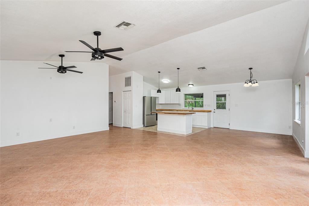 An open-concept living area features tile flooring, white walls, a kitchen island, and ceiling fans — 4085 CYPRESS BEND, GENEVA, FL