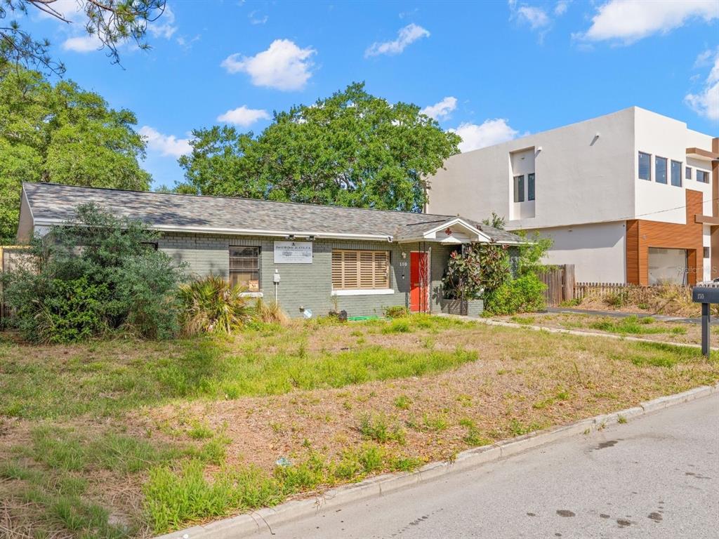 An empty room features light gray walls, tiled flooring, two windows with blinds, and corner shelving — 110 N LINCOLN AVENUE, TAMPA, FL