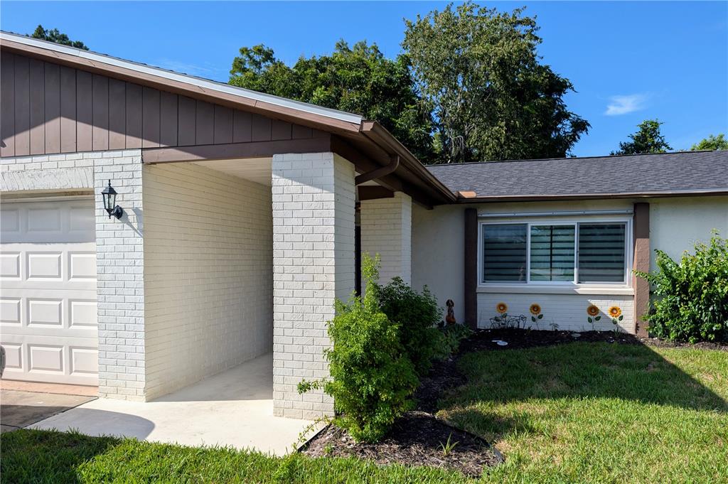 A single-story house with a white brick facade, a two-car garage, and a palm tree — 11608 FOX RUN, PORT RICHEY, FL